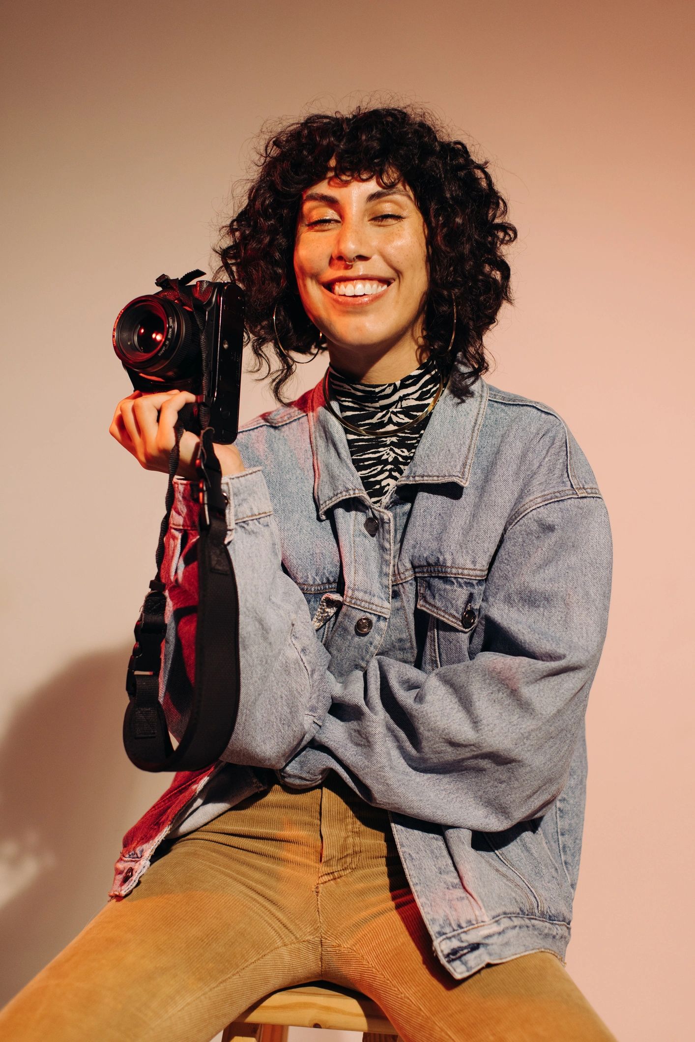 Professional photographer smiling while holding a camera in studio